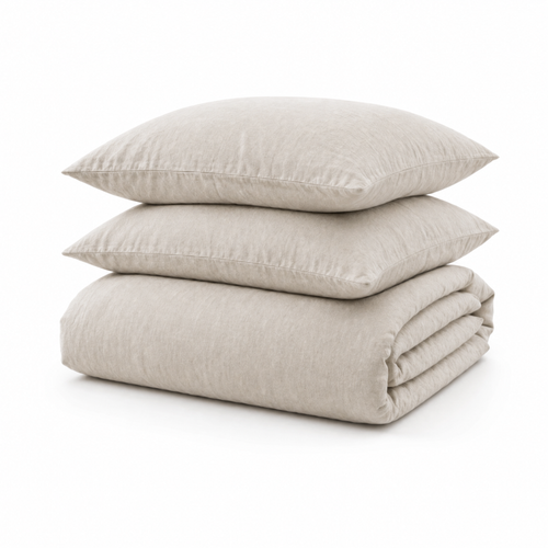 A stack of three light beige linen bedding pieces, including two pillows and a folded duvet cover, on a white background.