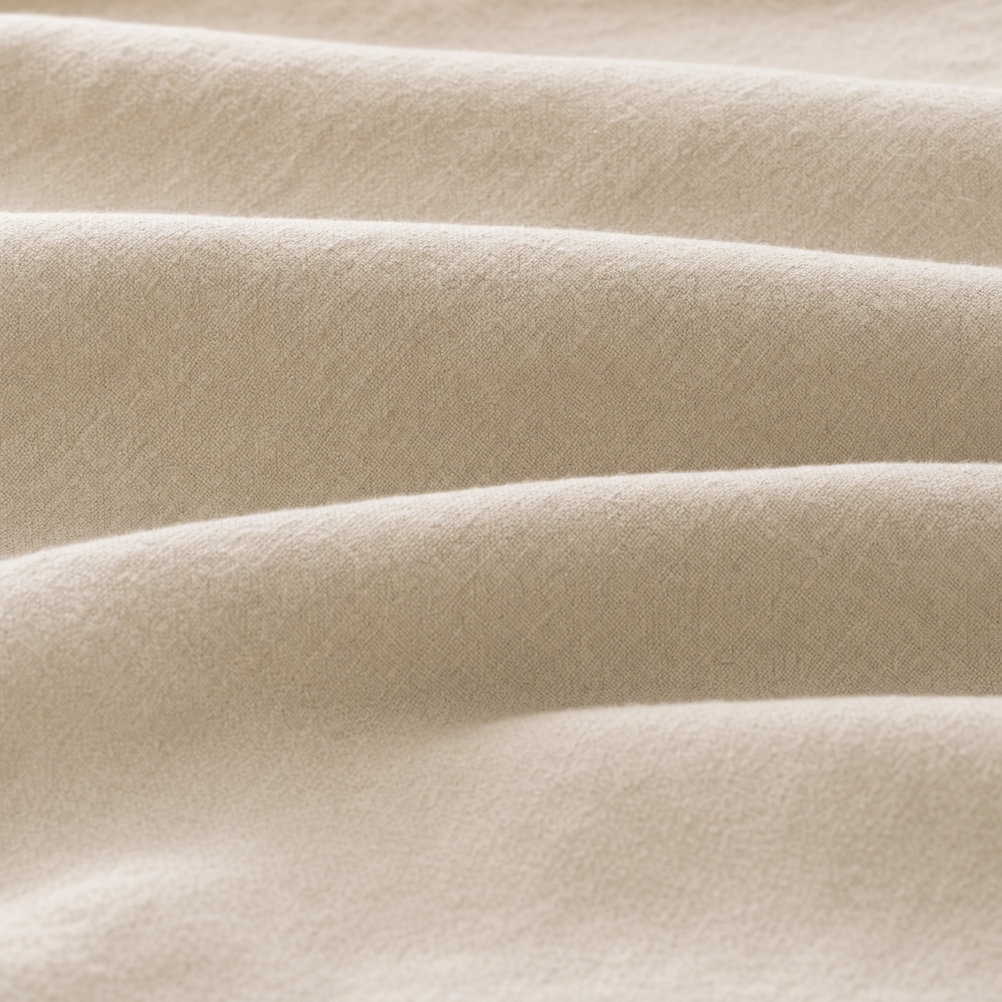 A close-up of fabric with soft folds and a fine textured weave.