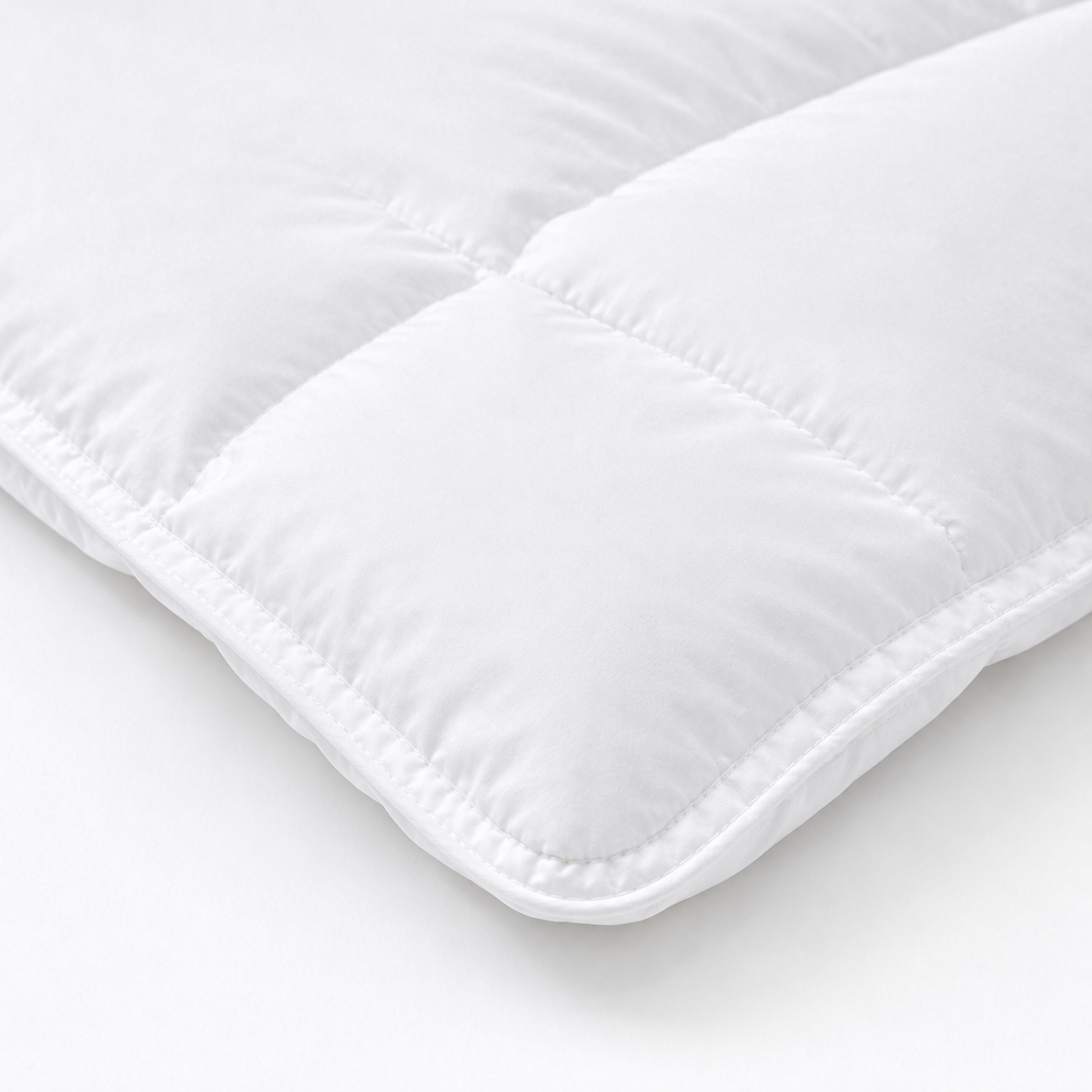 A close-up of a white quilted cushion or pillow corner with stitched padding, shown on a clean white background.