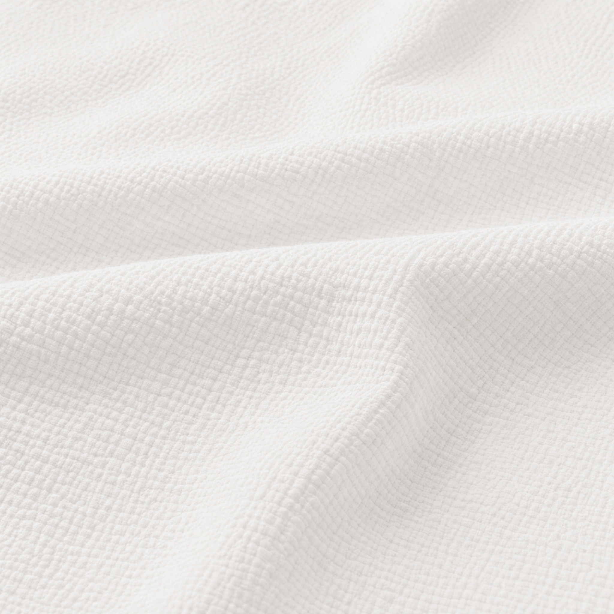 A close-up of white textured fabric with a fine woven grid pattern and soft folds.