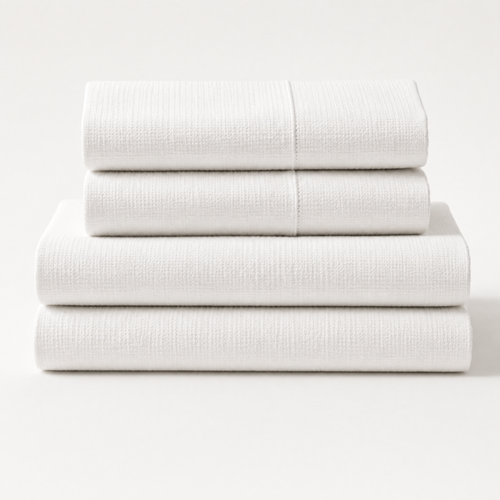 Three piece folded white textured bedding set stacked neatly on a clean white background.